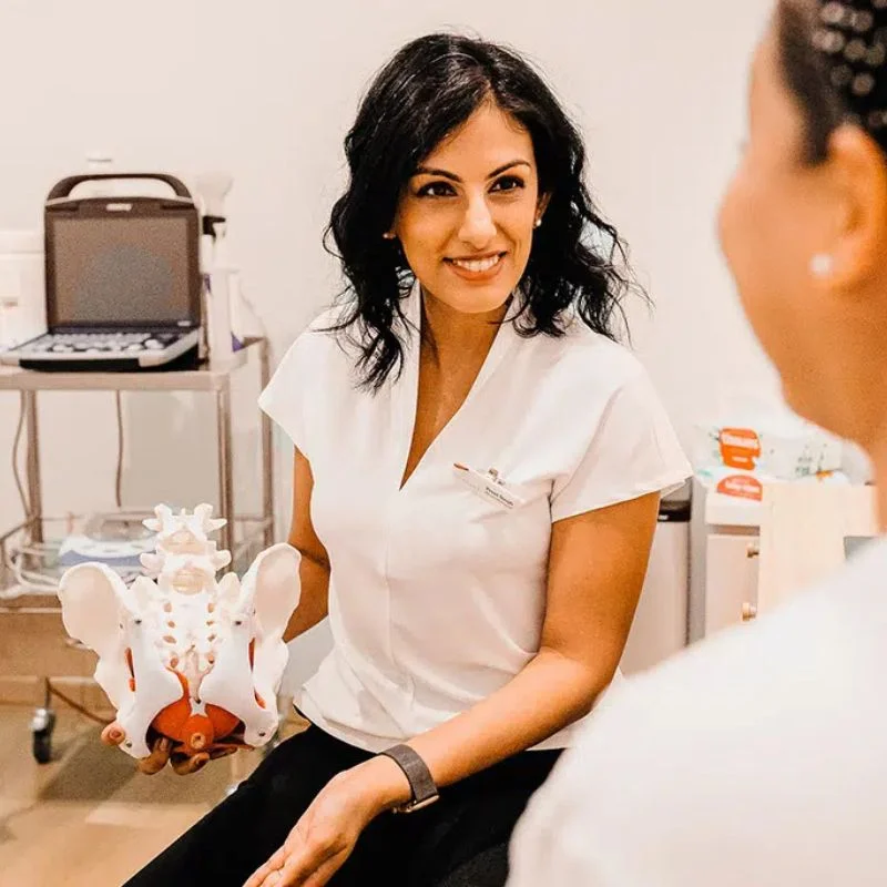pelvic floor physiotherapist holding pelvis model during patient consultation in Whitby