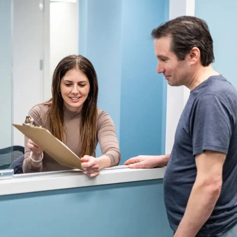 front desk staff assisting patient with clinic intake form at Kinesis Rehab Whitby