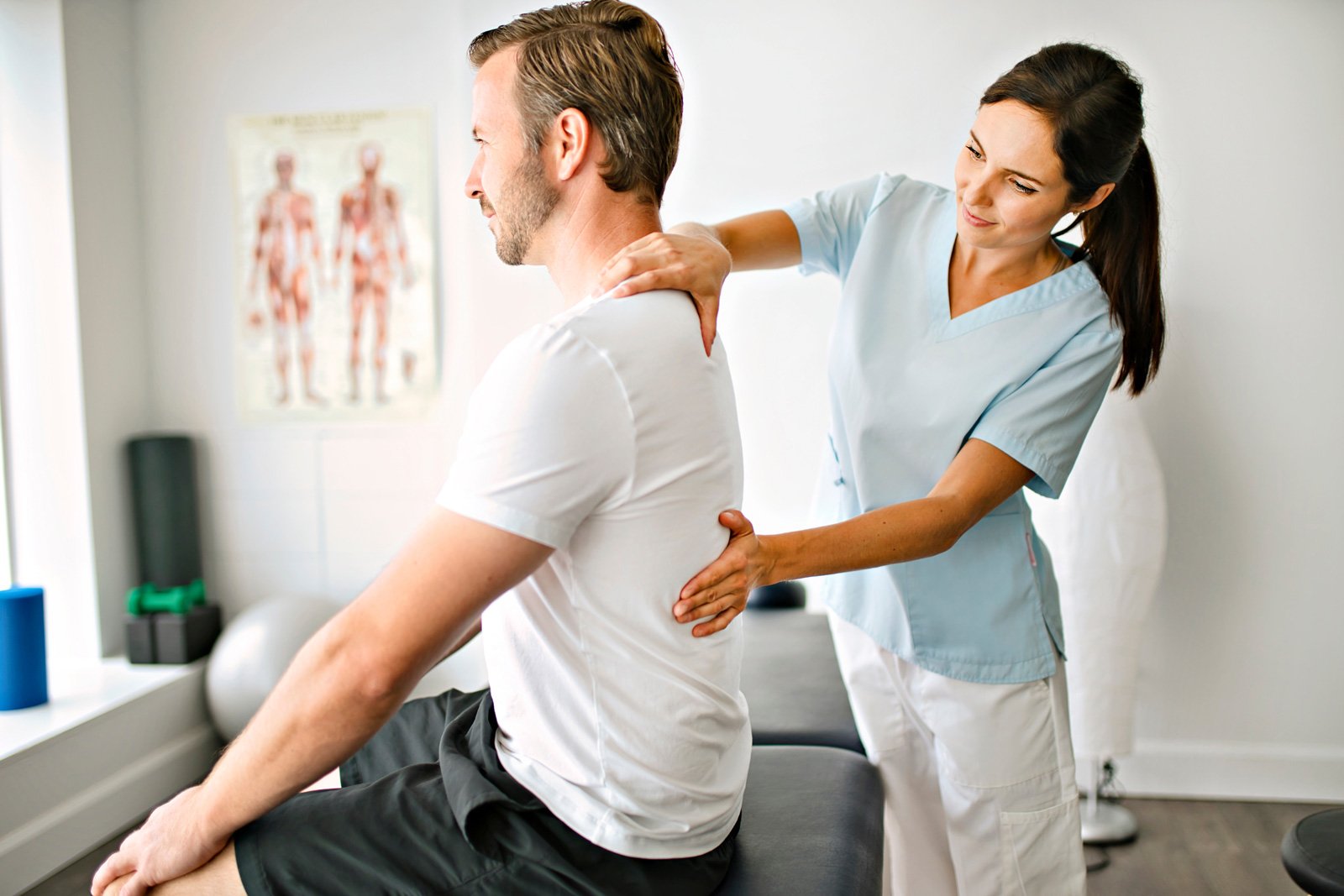 Physiotherapist assessing a patient's shoulder and back posture during a physiotherapy appointment